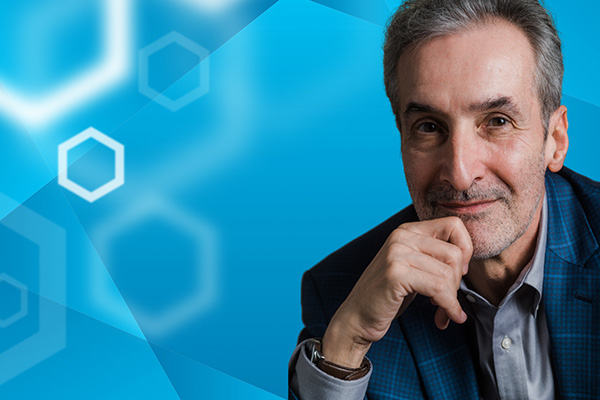 Professor Samuel Freedman pictured on the right of a blue background with white hexagons overlayed.